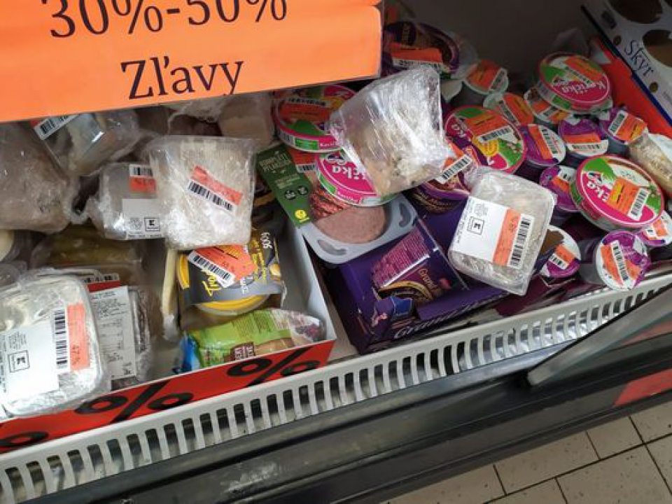 Znečistené chladiarenské zariadenie s vystavenými lahôdkarskými výrobkami na predajnej ploche.