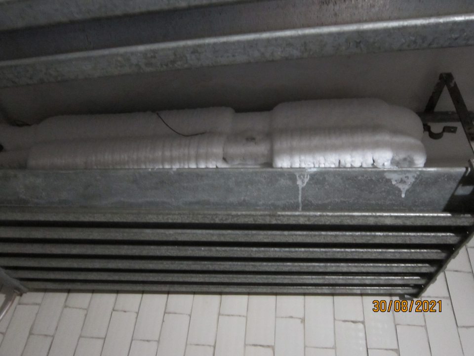 Kondenz kvapkajúci z chladiarenskej jednotky v chladiacom boxe na mliečne výrobky zachytávaný do nekrytého vedra.