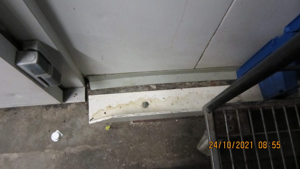 V suchom sklade pred dverami mraziaceho boxu silne znečistená podlaha, silne znečistená kovová konštrukcia vozíka s výskytom korózie.   