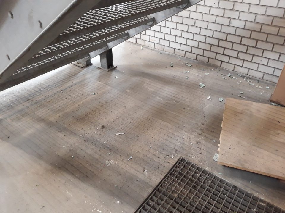 Znečistená podlaha pod schodišťom a za zábranami na príjme tovaru