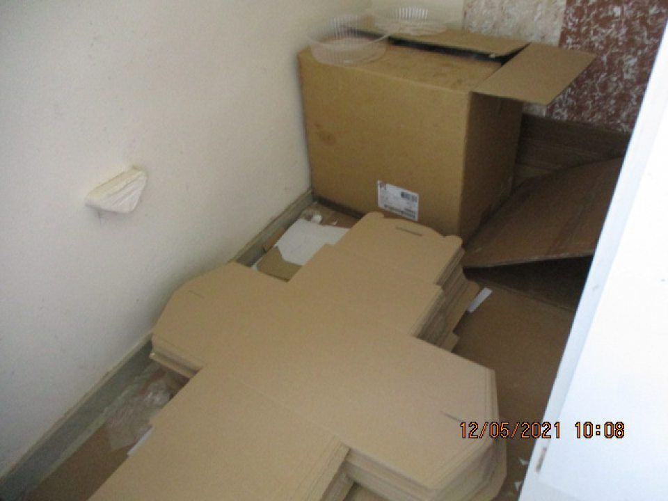 Obalový materiál - kartónové obaly používané na balenie finálnych výrobkov uložené na tenkom kartóne na podlahe v dennej miestnosti pre zamestnancov.Na podlahe v okolí uloženého obalového materiálu zistený nános prachu a nečistôt.