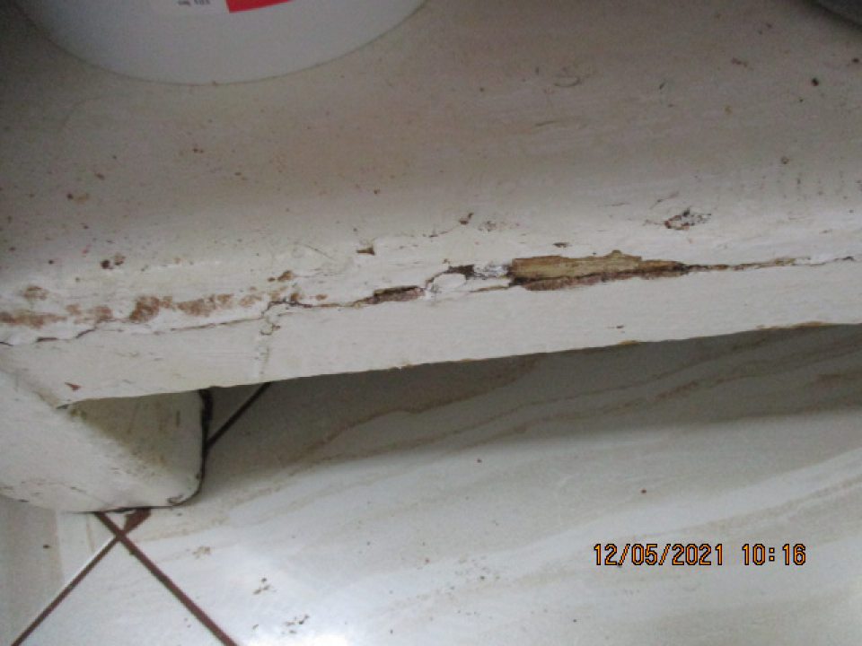 Vo výrobných priestoroch olupujúci sa hygienický náter pracovného stola, poškodená hrana - ulomený drevený povrch