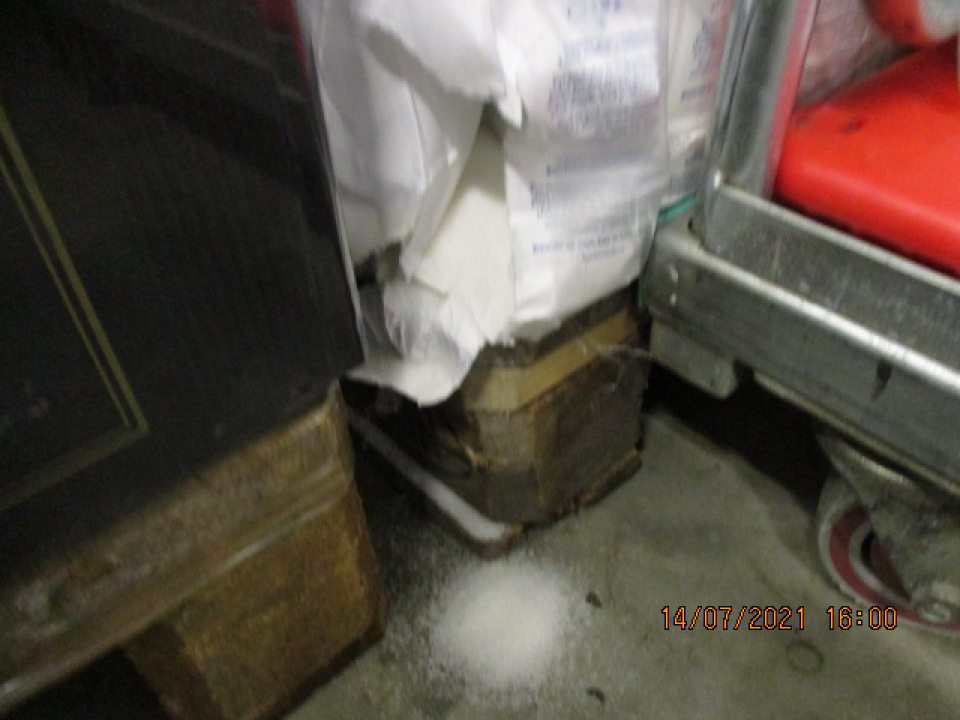 v zázemí vľavo od stĺpu umiestnená paleta s uloženými potravinami, v spodnej časti uložený kryštálový cukor( poškodené spotrebiteľské balenie)vysypané na podlahe