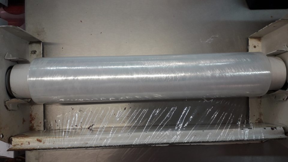 Stojan na baliacu fóliu je znečistený vrstvou zasušených zvyškov potravín.