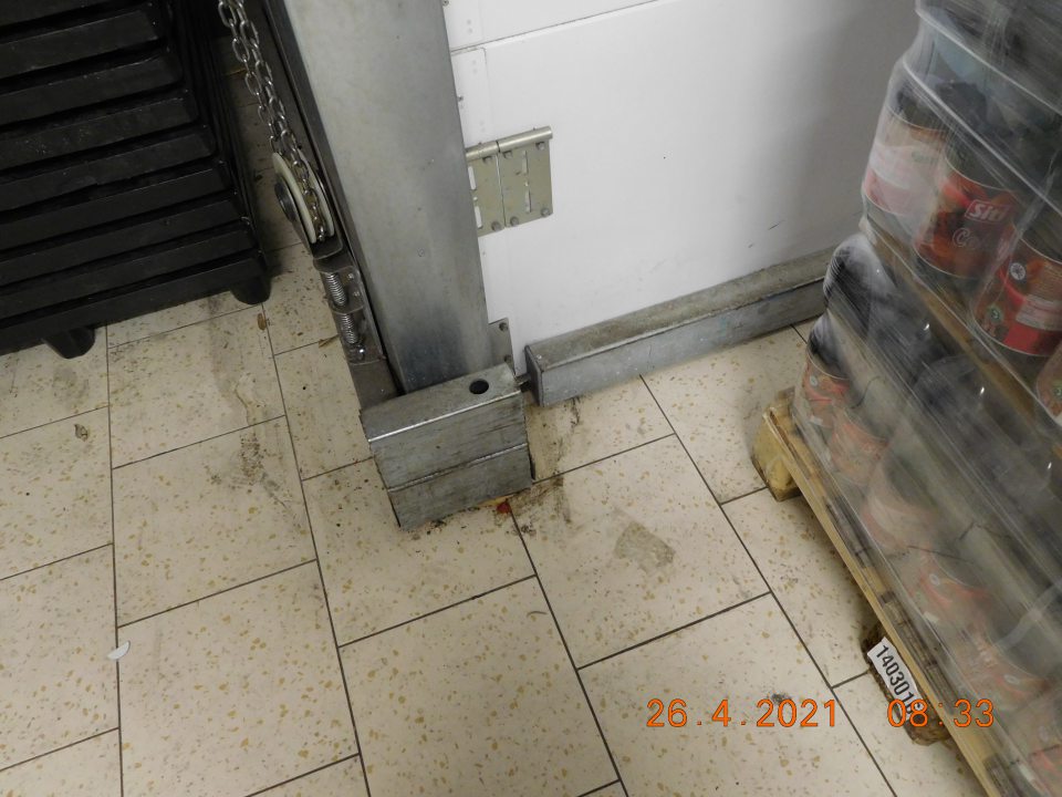 Podlaha v sklade na viacerých miestach znečistená prachom, omrvinkami, zvyškami kartónových obalov, čiernymi pásmi od manipulačných vozíkov. 