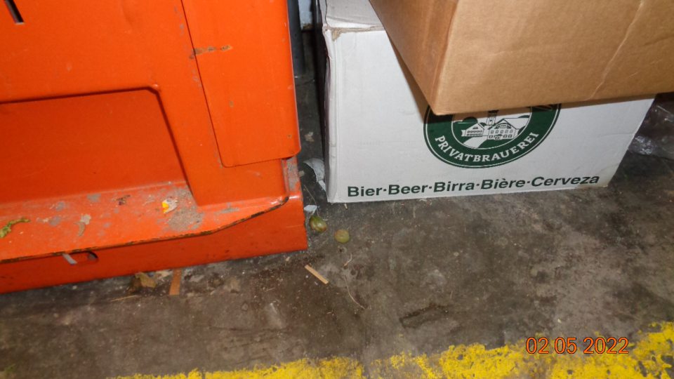 Podlaha na viacerých miestach v sklade znečistená čiernou špinou, zvyškami obalov a potravín