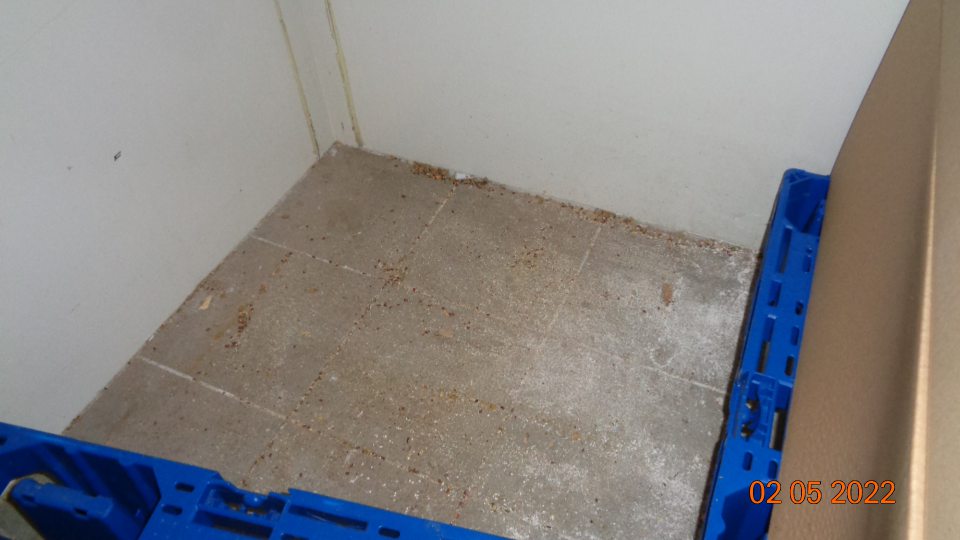 Podlaha v mraziacom boxe znečistená množstvom omrviniek a zvyškov z dopeku.