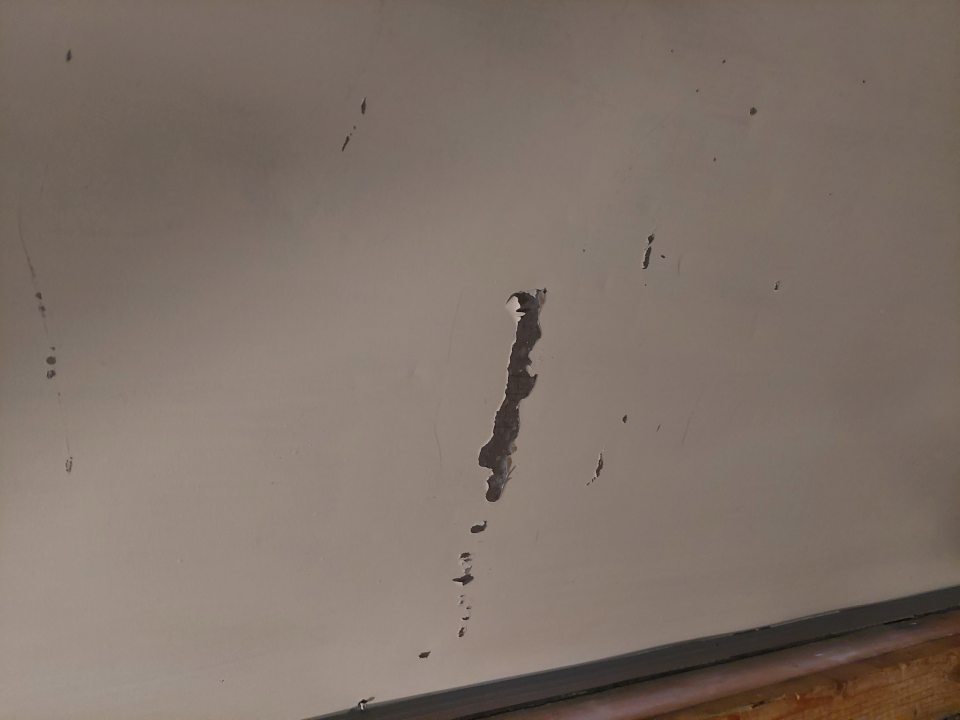 Poškodený povrch dverí na chladiacom boxe s výskytom korózie.
