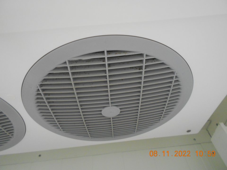 Zistená znečistená stropná klimatizačná jednotka v zabudovanom chladiarenskom boxe s uchovávanými mliečnymi výrobkami v zázemí predajne. 