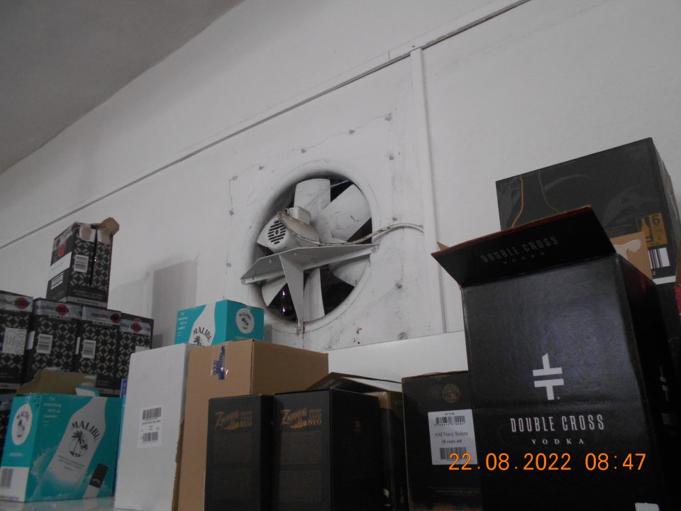 Silne znečistené vetracie zariadenie na stene pri regáloch s uchovávanými alkonápojmi.