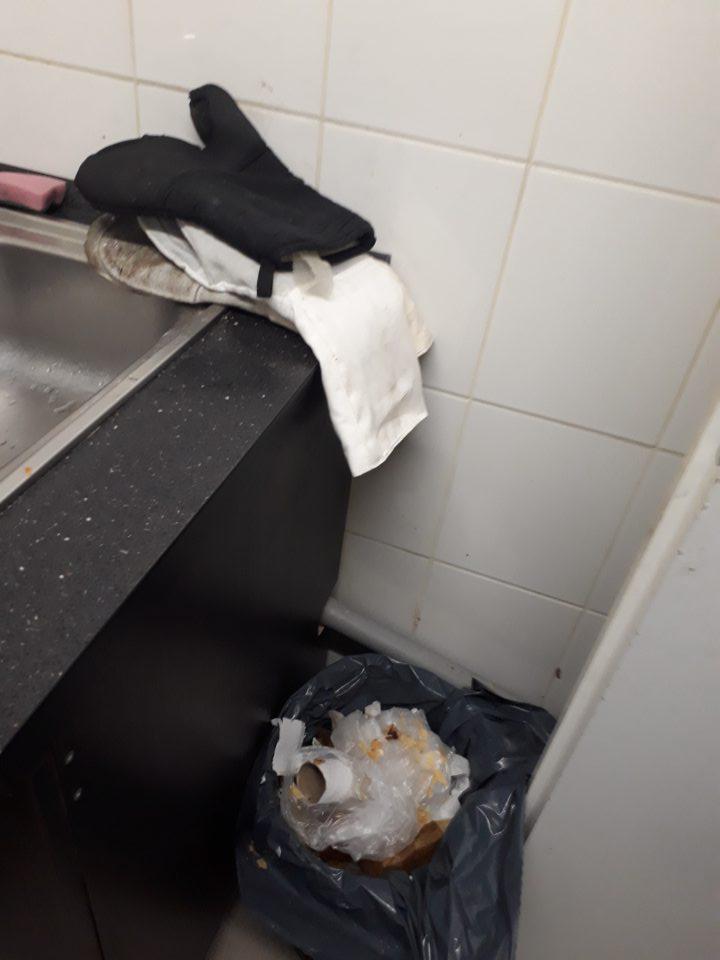 Vo výrobnej časti dopeku odkrytý preplnený kôš, rukavice uložené na umývadle.