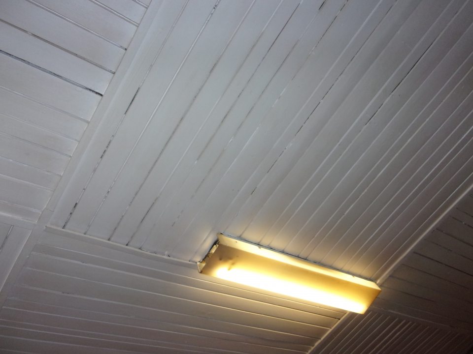 Poškodený a znečistený kryt svietidla vo výrobnej hale.