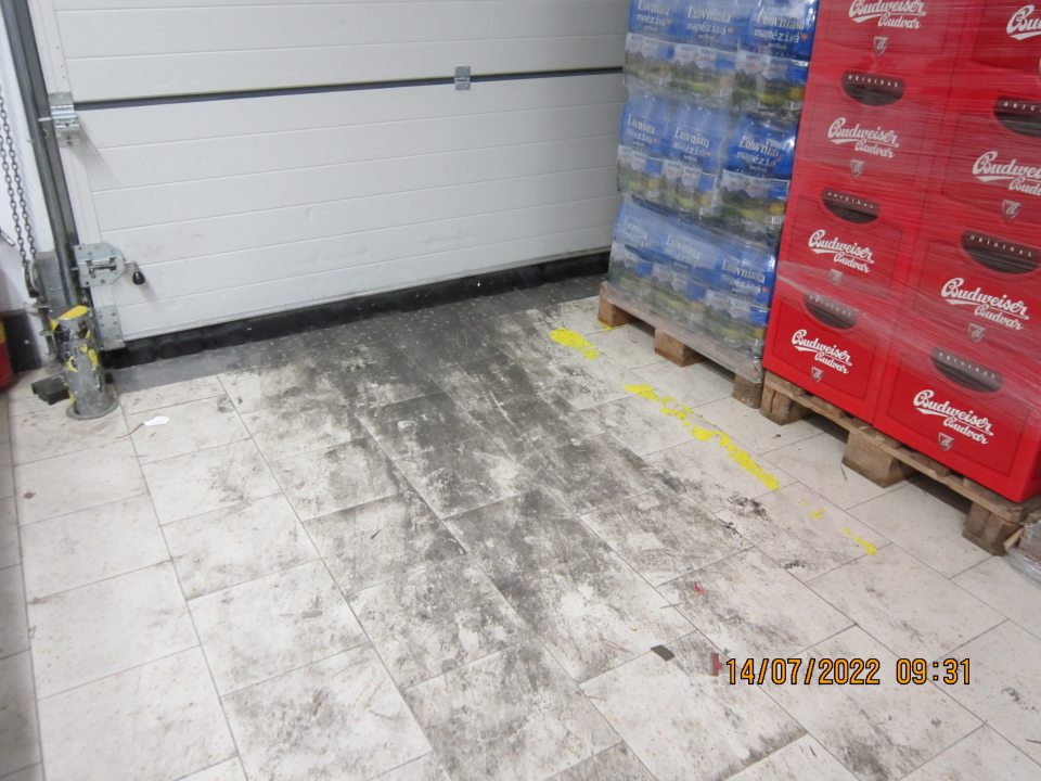 V skladovacích priestoroch pri rampe podlaha znečistená prachom a nánosmi zaschnutej čiernej špiny. 