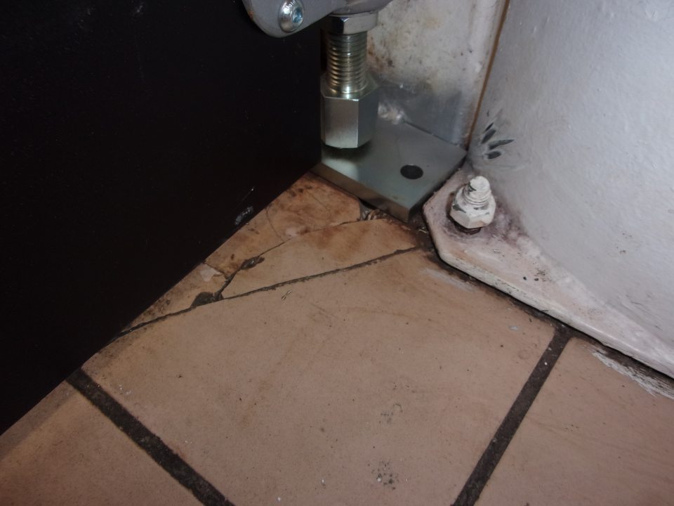 Porušená celistvosť dlažby v mieste prechodu z predajnej plochy do zázemia obchodného domu v rohu.