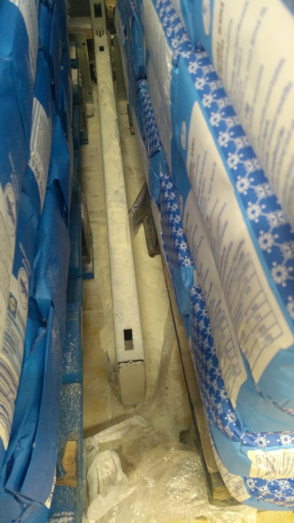 Podlaha na predajnej ploche - znečistenie zvyškami po rozsypaní výrobkov medzi paletami s múkou.