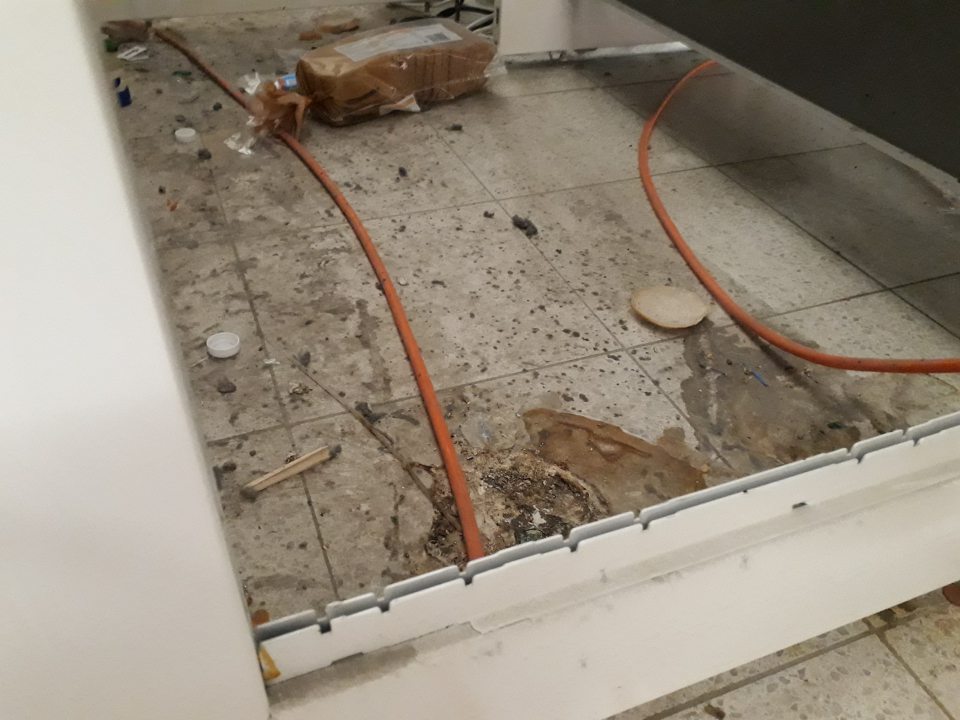 Nevyhovujúci hygienický stav podlahy na ťažko dostupných miestach za paletou s trvanlivým mliekom - podlaha znečistená hrubou vrstvou prachu, mechanickými nečistotami, zvyškami obalov po výrobkoch.