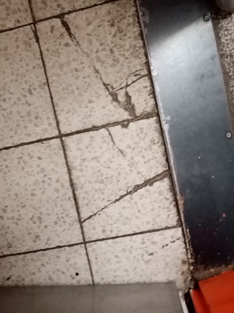 Nevyhovujúci stav podlahy v zázemí predajne pri vstupe do suchého skladu zo zázemia - porušená celistvosť podlahy - praskliny.
