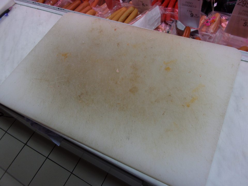 Opotrebovaná doska na krájanie pri mäsovom pulte.