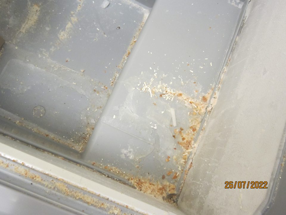 Nánosy námrazy so zbytkami omrviniek, semien a drobných častí z uchovávaného mrazeného polotovaru v mraziacom zariadení.