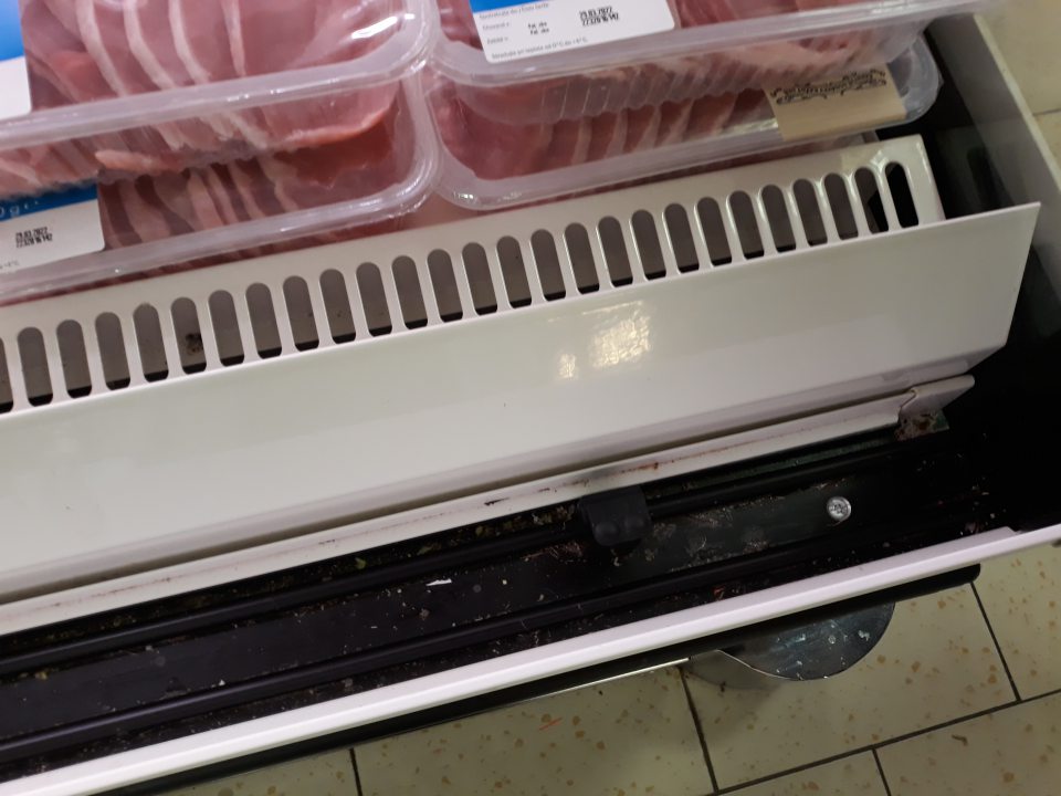 Znečistená úložná plocha, mriežka a vodiaca lišta chladiaceho zariadenia pre predaj mäsa a rýb.