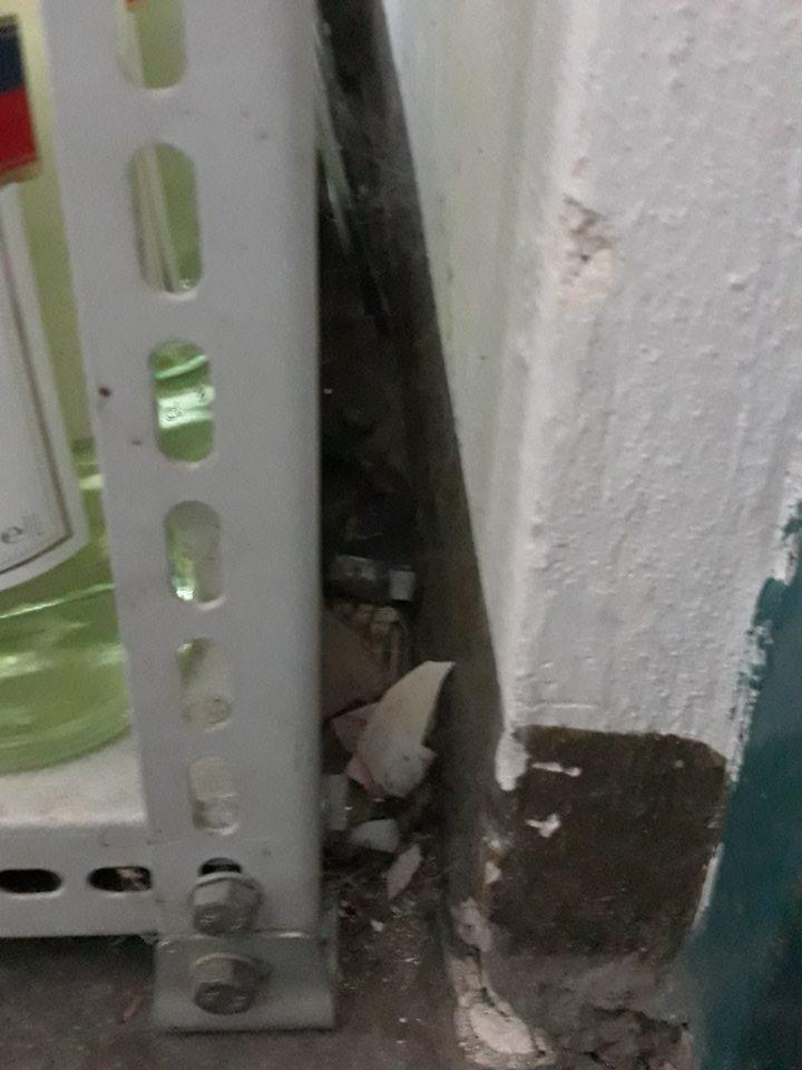 V sklade, podlaha vedľa vstupných dverí medzi stenou a regálom znečistená prachom, nečistotami, obalovým materiálom a mechanickými nečistotami.