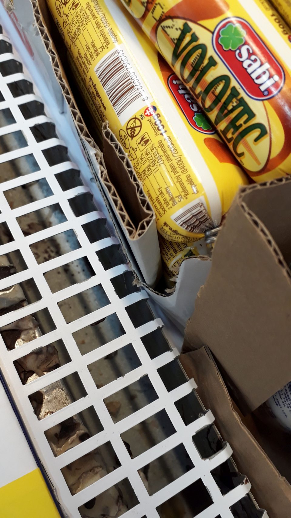 Nečistoty a zvyšky rozliatého mliečneho výrobku pod mriežkou v chladiacom zariadení pre mlieko a mliečne výrobky.