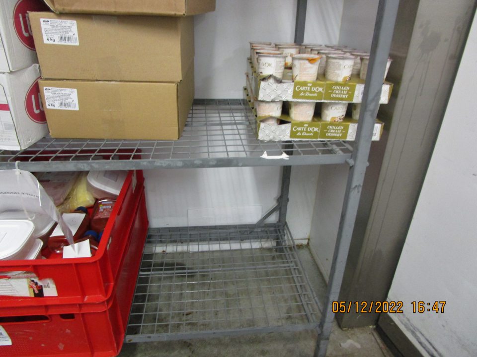 v zázemí prevádzky v chladiacom boxe s uskladnenými mliečnymi a mäsovými výrobkami značne znečistená podlaha vyliatou tekutinoun a v pravom rohu nános špiny a nečistôt