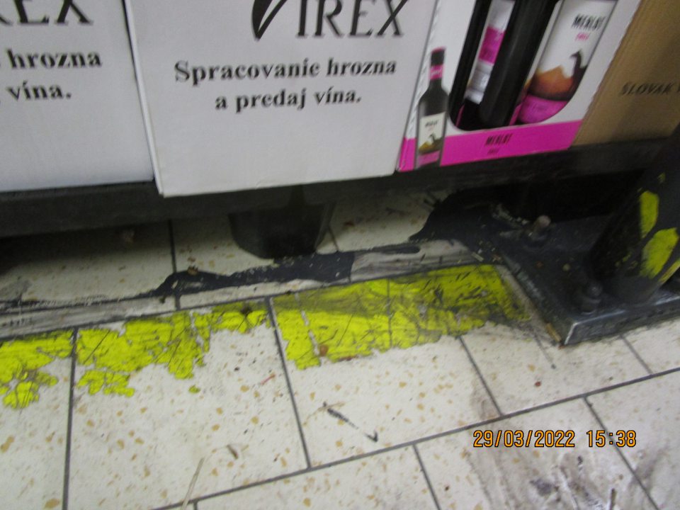 v zázemí pri paletách s alkoholickými nápojmi a pivom znečistená podlaha vyliatou čiernou farbou -