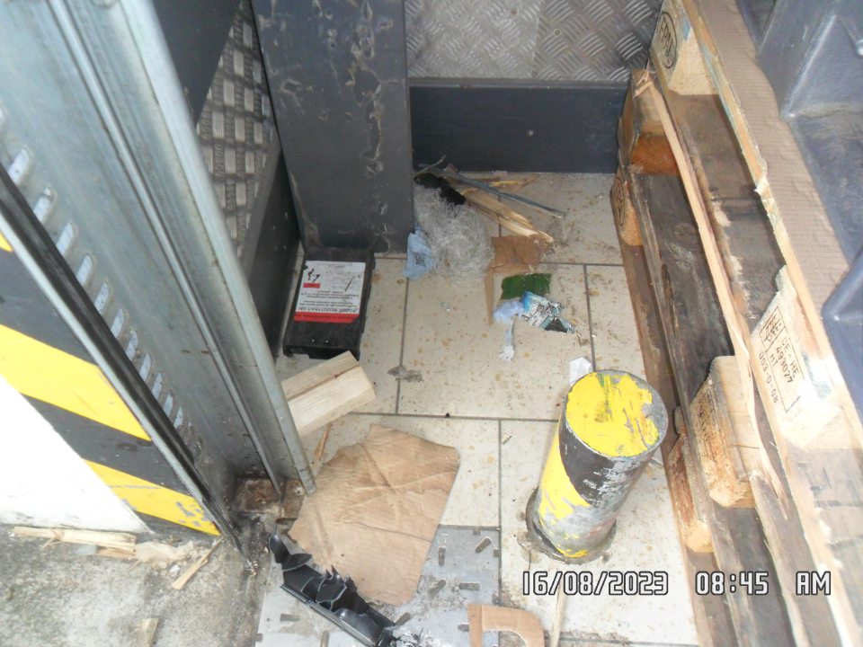 Podlaha na príjme a vedľa príjmových dverí znečistená mechanickými nečistotami, prachom, obalovými materiálmi a kúskami drevených paliet.