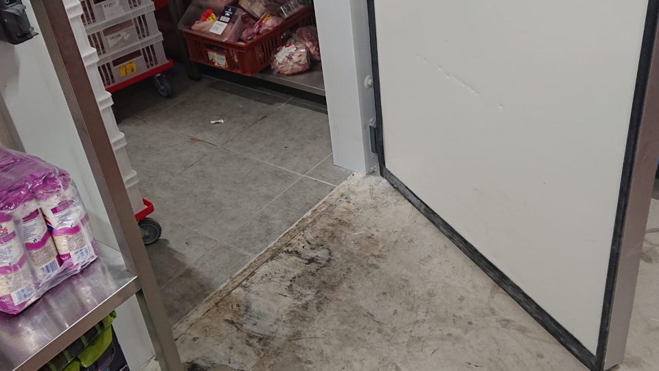 V skladových priestoroch pri vstupe do chladiaceho boxu s mäsom a mäsovými výrobkami znečistené podlaha.