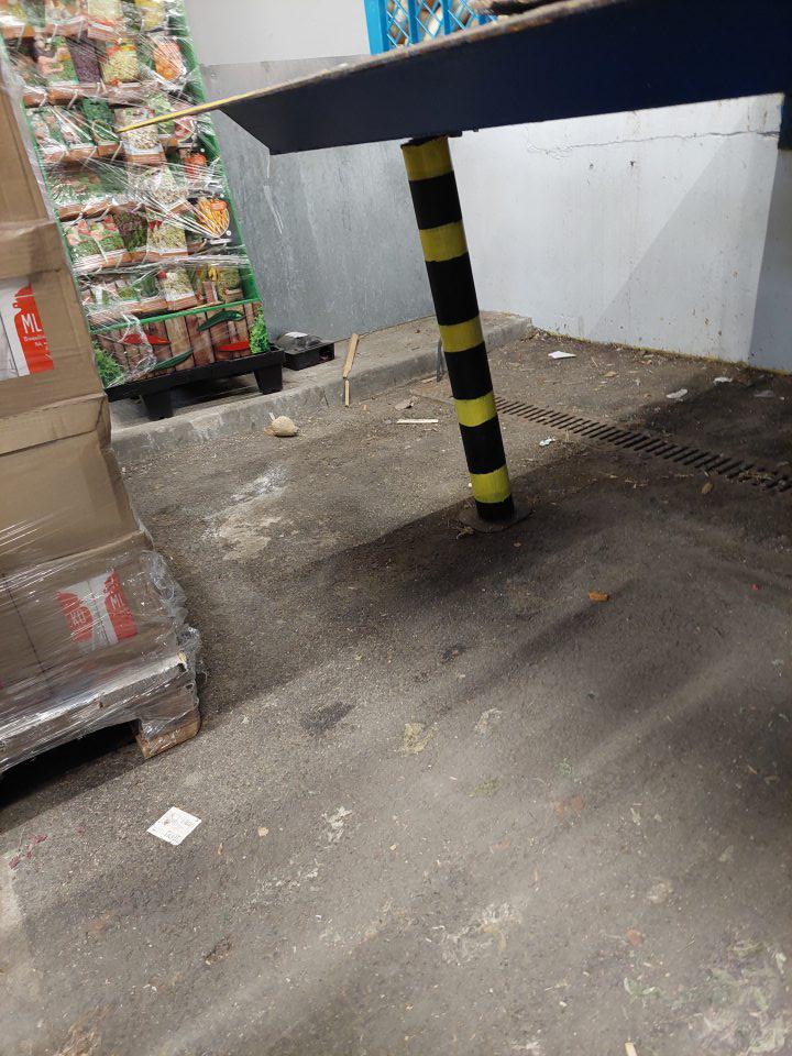 V skladových priestoroch pod rampou, v okolí dverí a medzi paletami znečistená podlaha.