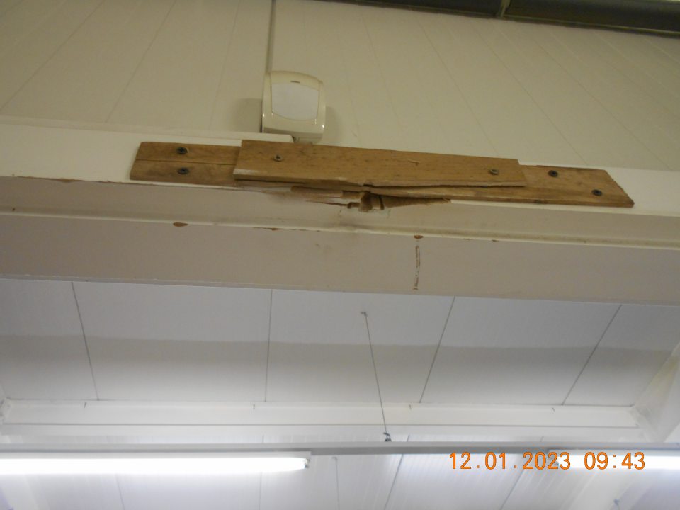  Poškodená vrchná časť zárobne dverí, vedúcich do skladu predajne, v dôsledku čoho nie je možné ich uzatváranie. 