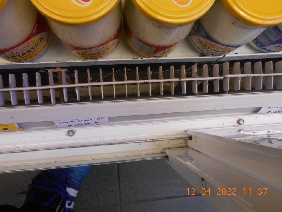 Skorodovaná drážka a olupijúci sa náter s výskytom korózie na regálových policiach v chladiarenskej vitríne s uchovávanými mliečnymi výrobkami. 