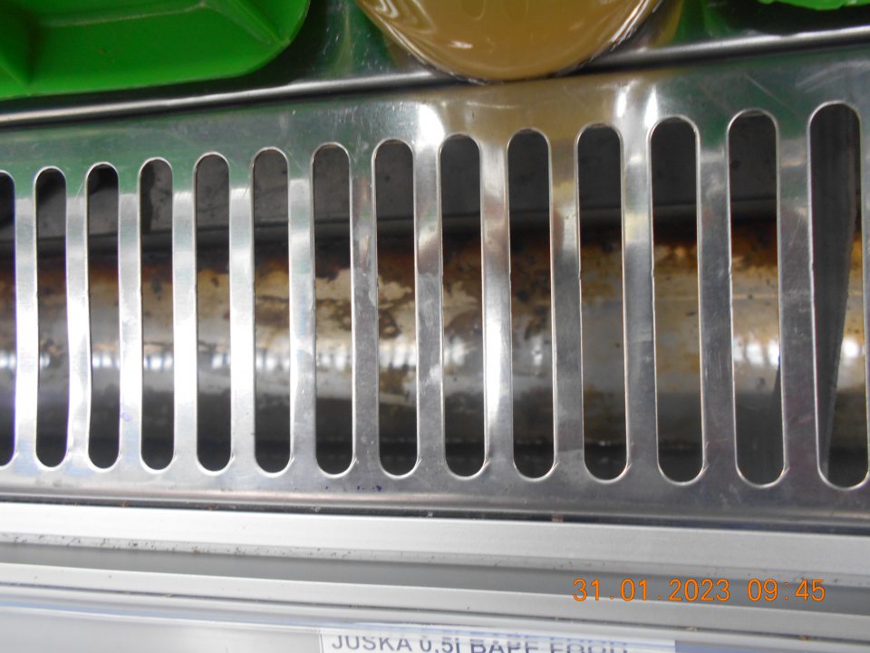 Znečistená chladiarenská vitrína uchovávanou čerstvou zeleninou a ovocím v ťažko dostupných miestach, pod mriežkou. 