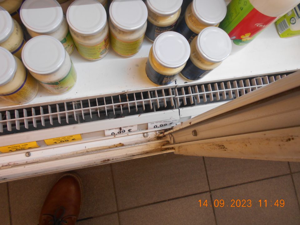 V čase kontroly zistený nedostatok: - znečistené chladiarenské zariadenie (mriežka a pod mriežkou ako aj na koľajničkách posuvných dverí výskyt rozliateho obsahu mliečnych výrobkov a prach) ako aj skorodovaný rám posuvných dverí v chladiarenskej vitríne s uchovávanými mliečnymi výrobkami