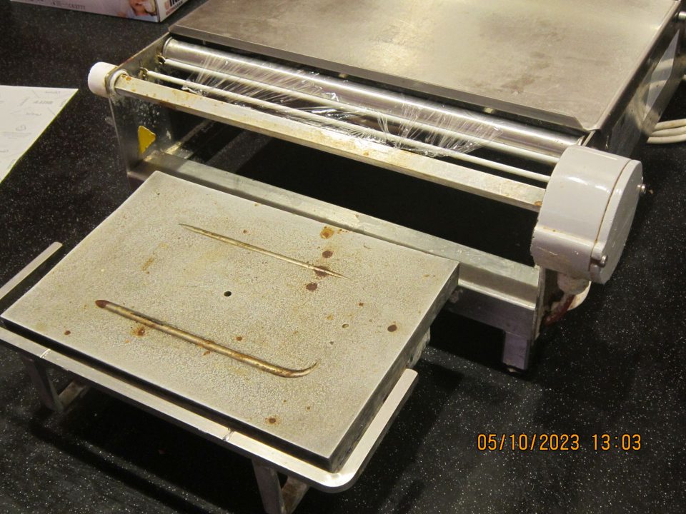  znečistené vyhrievacie teleso na baliacom zariadení v mäsovom kútiku nečistotami dlhodobého charakteru.