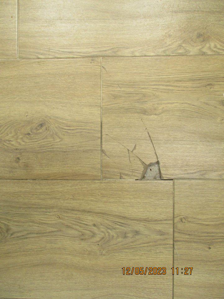 Poškodená podlaha pred lahôdkovým pultom.