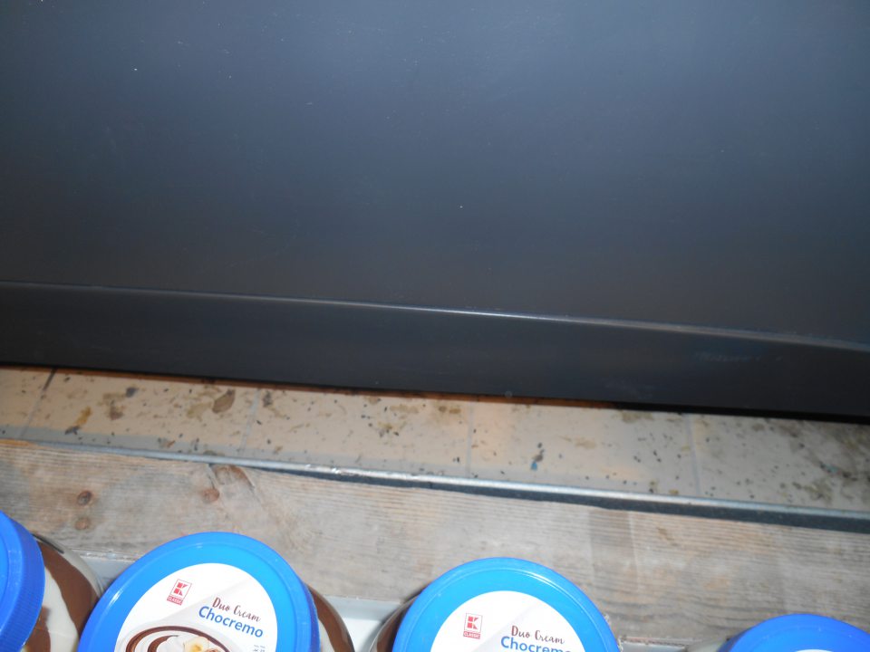 Hygiena predaja - trus hlodavcov na podlahe na predajnej ploche za drevenou paletou, na ktorej sú umiestnené čokoládové nátierky.