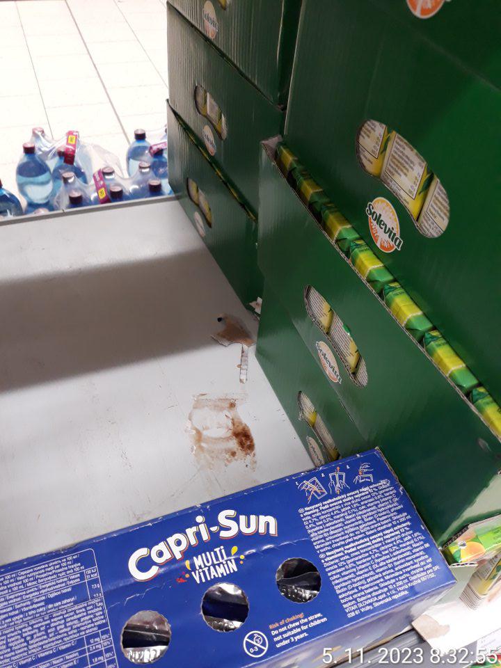 Znečistenie regálu pri predaji nealkoholických nápojov (Cola, Caprisone) potečením obsahu.