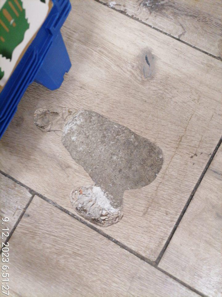 Porušená celistvosť dlažby pred vstupom do skladu z predajnej plochy.