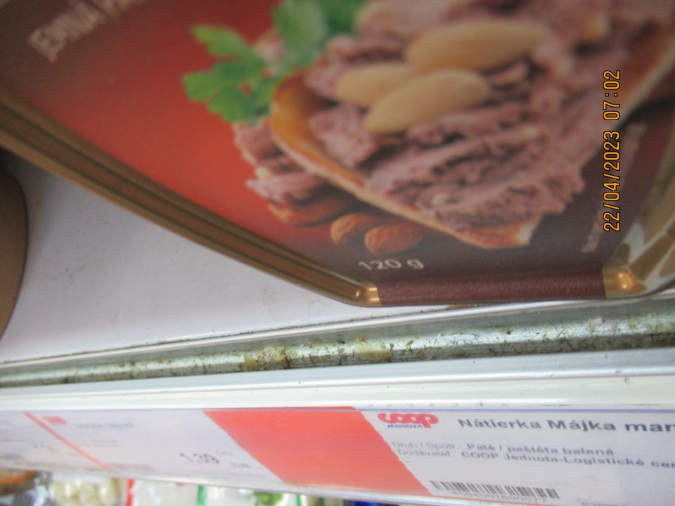 Znečistenie drážok za lištou na cenovky chladiaceho zariadenia na predajnej ploche.