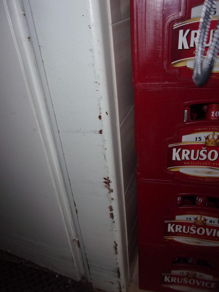 Poškodený náter na zárubniach pri vstupe do skladu.