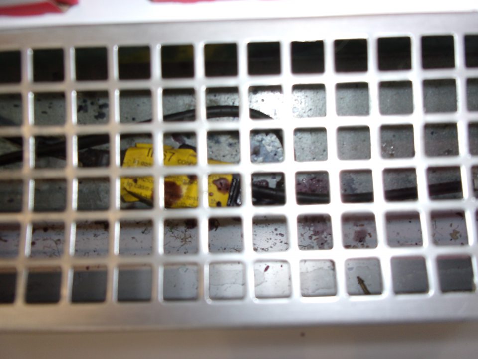 Znečistený priestor pod mriežkami v chladiacej vitríne.