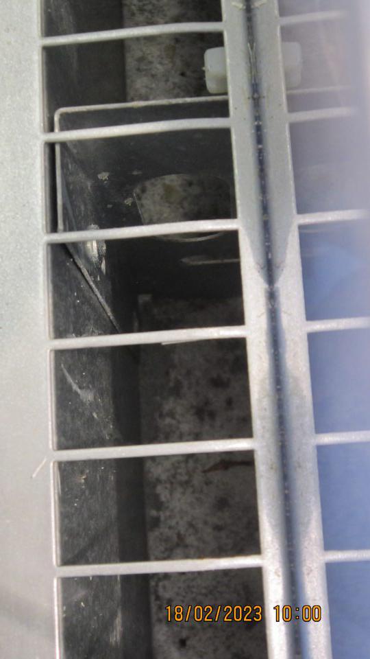 Na predajnej ploche v časti predaja mliečnych výrobkov v otvorenom chladiacom zariadení znečistený priestor pod mriežkou a kovová konštrukcia mriežky prachom, zaschnutou špinou a napadanými nečistotami.