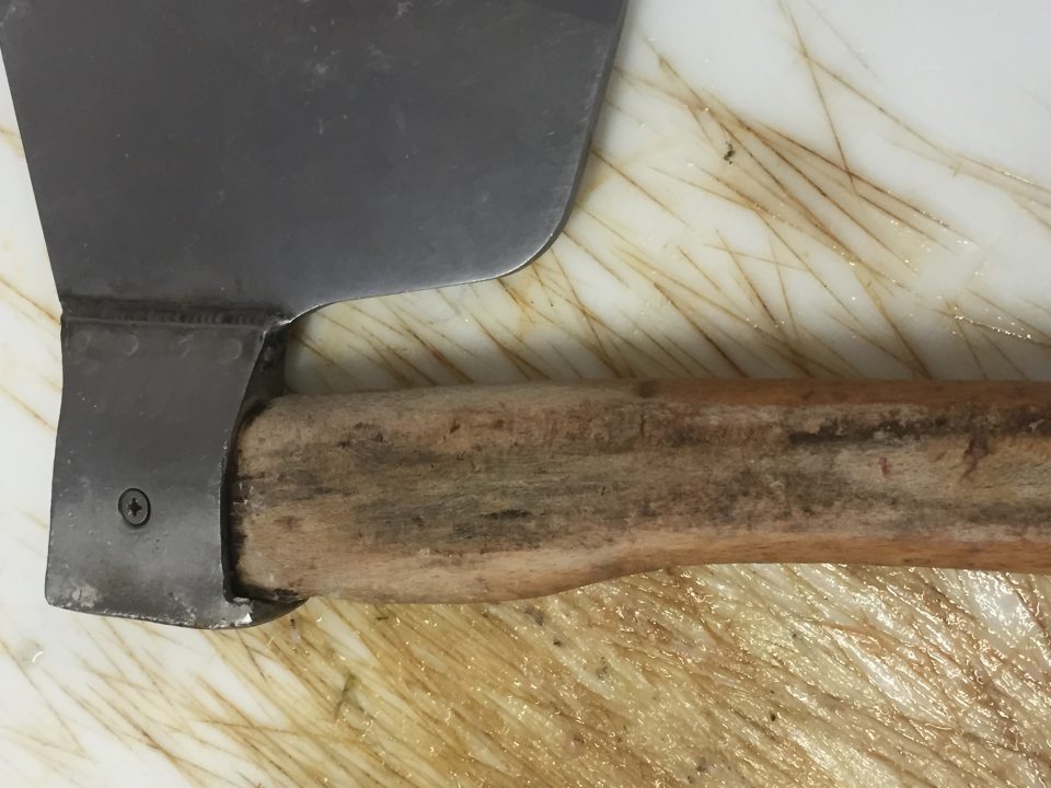 Poškodená a  znečistená  drevená rukoväť  sekáča na mäso.