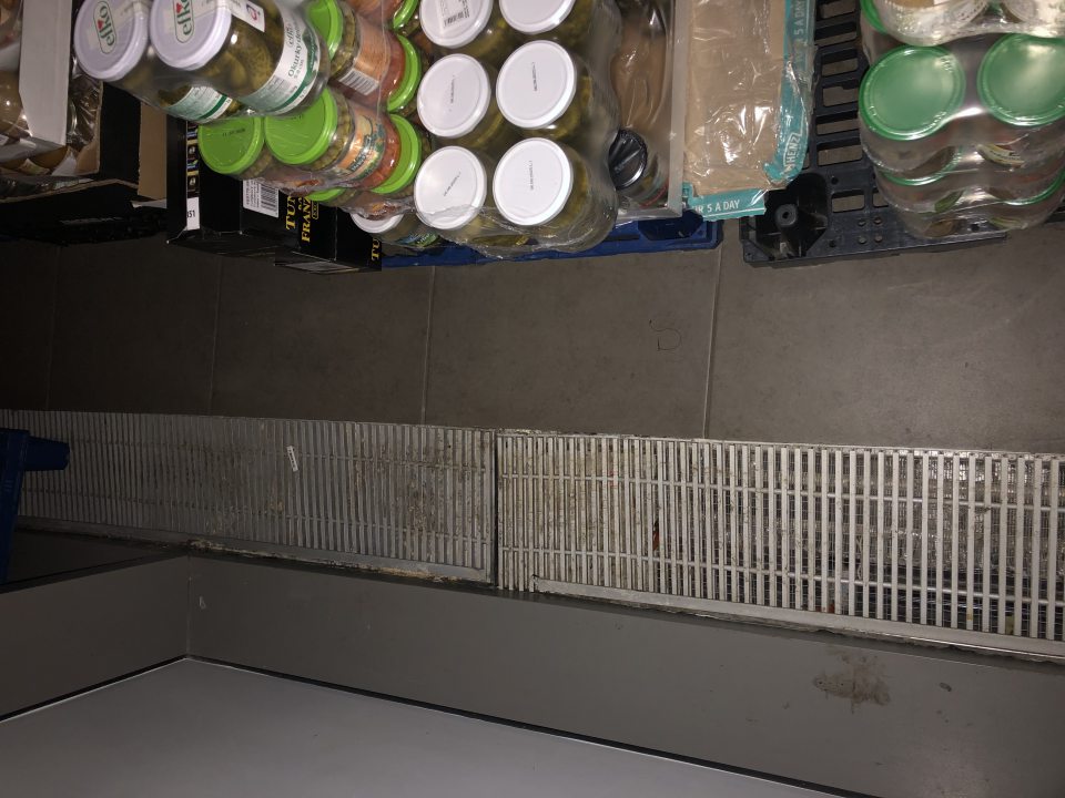  Predajná plocha - znečistená podlaha a podlahové plastové mriežky nachádzajúce sa za regálmi.