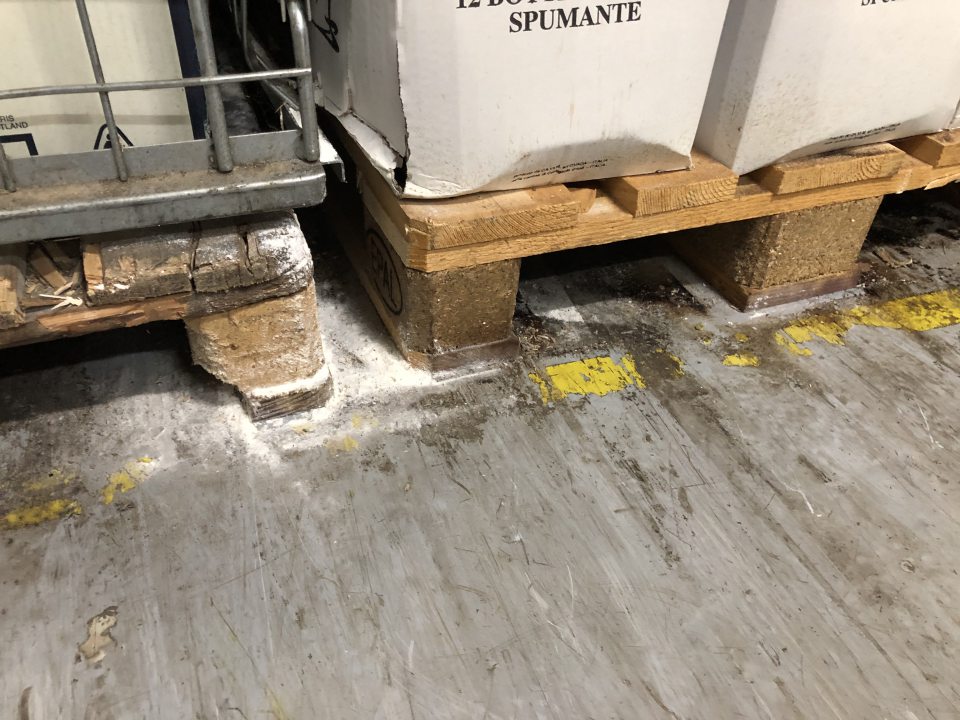 Znečistená podlaha v sklade pod paletami.