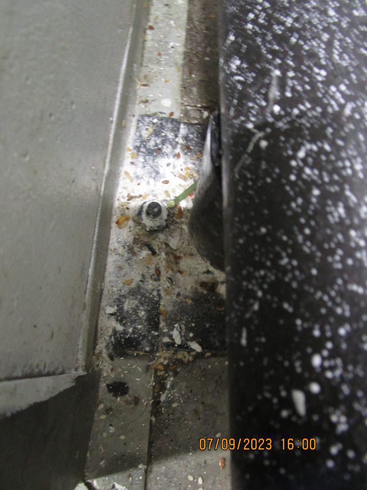 v sklade za kovovými klietkami so zálohovanými fľašami - podlaha a kovové zábrany značne znečistené bielou farbou a zvyškami igelitu