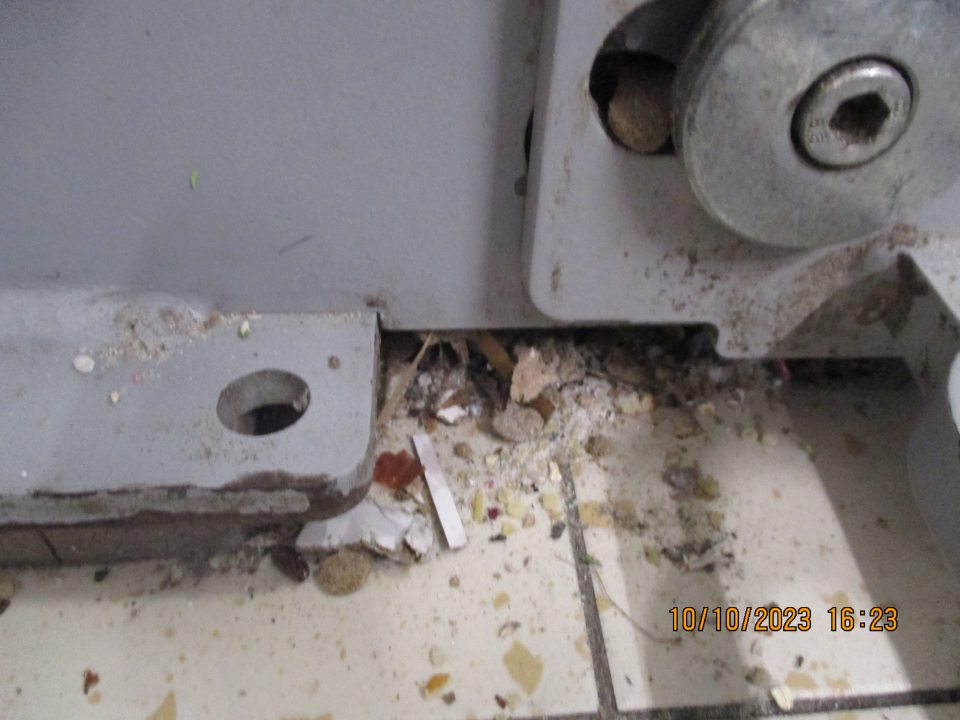 Pri vstupných dverách lis na kartónové obaly, znečistený nánosom prachu, nečistôt a častí kartónov. 