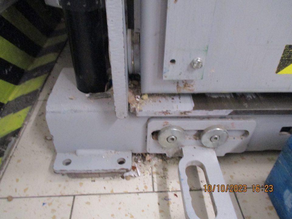 Pri vstupných dverách lis na kartónové obaly, znečistený nánosom prachu, nečistôt a častí kartónov 